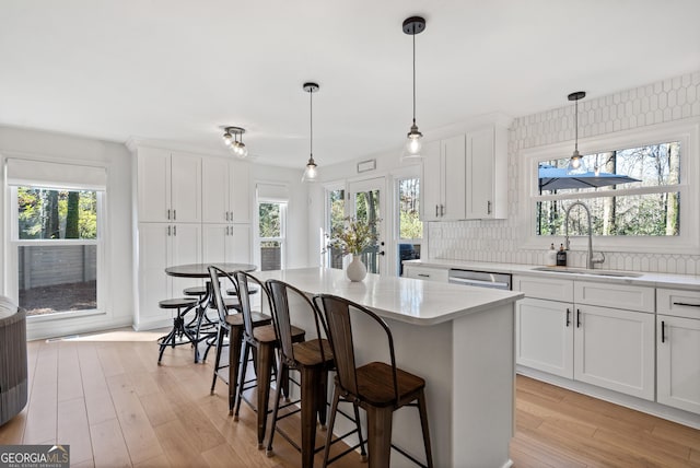 kitchen with white cabinetry, a center island, light wood-type flooring, and a sink