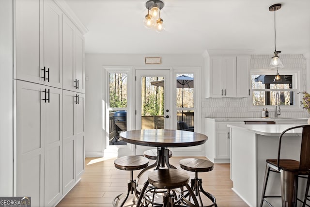 kitchen featuring light countertops, white cabinets, light wood-type flooring, and a wealth of natural light