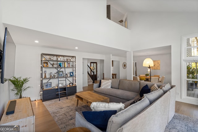 living room with recessed lighting, high vaulted ceiling, wood finished floors, and stairs