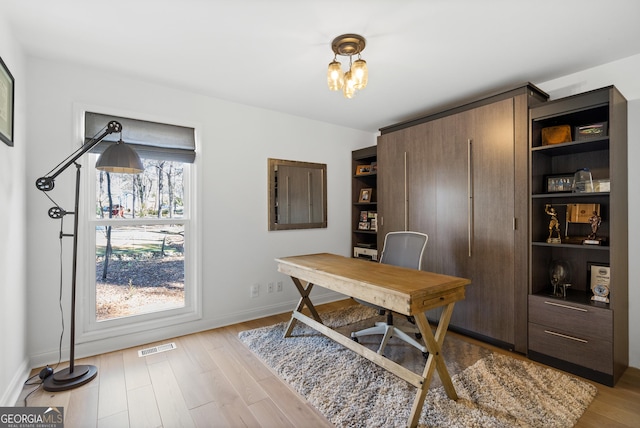 office featuring visible vents, baseboards, light wood-type flooring, and an inviting chandelier