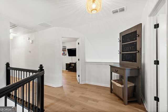 corridor with visible vents, an upstairs landing, attic access, and wood finished floors