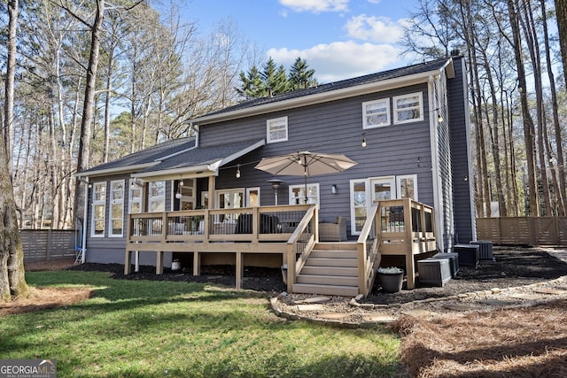 rear view of property featuring a chimney, a wooden deck, a yard, and fence