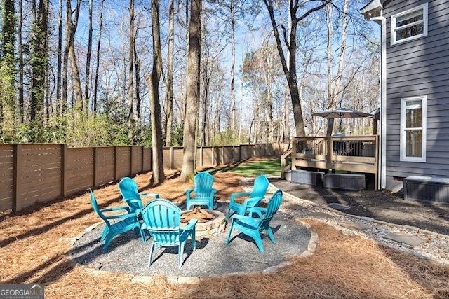 view of yard featuring a fire pit, a fenced backyard, and a wooden deck