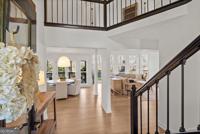 entrance foyer featuring light wood-style floors, a towering ceiling, and stairs