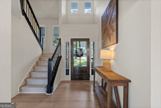 foyer featuring a high ceiling, stairway, wood finished floors, and baseboards