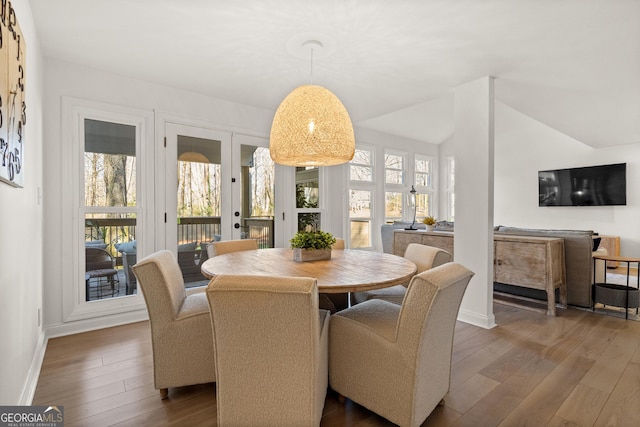 dining space featuring vaulted ceiling, wood-type flooring, and a wealth of natural light