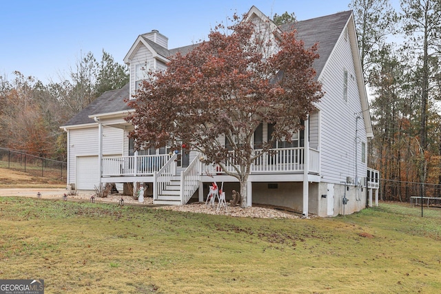 view of front of property featuring covered porch, a front yard, fence, and a garage