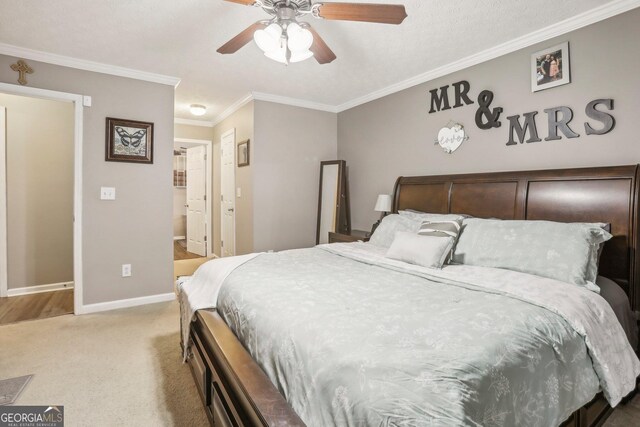 bedroom with light carpet, baseboards, a ceiling fan, ensuite bathroom, and crown molding