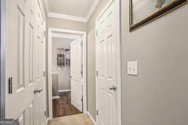 hallway featuring a textured ceiling, wood finish floors, baseboards, and crown molding