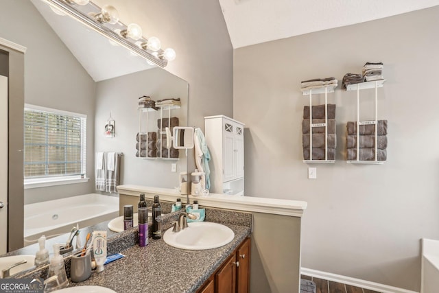 bathroom with a bath, double vanity, vaulted ceiling, and a sink