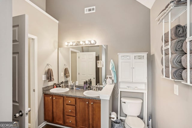 full bath with toilet, double vanity, a sink, and visible vents