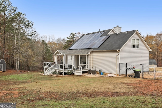 back of house featuring solar panels, a lawn, a gate, fence, and a wooden deck