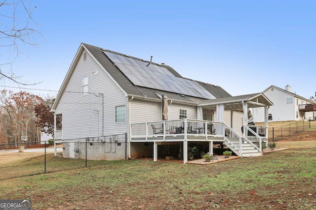 back of property featuring solar panels, stairway, a yard, fence, and a wooden deck