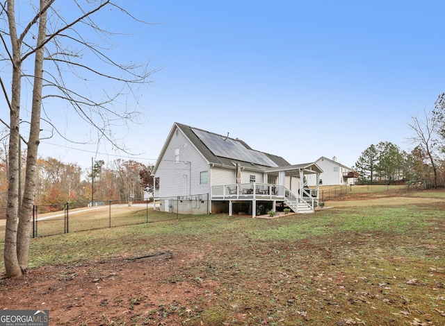 rear view of house with a deck, a yard, and fence