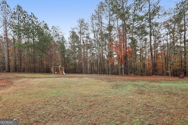 view of yard with a forest view and a playground