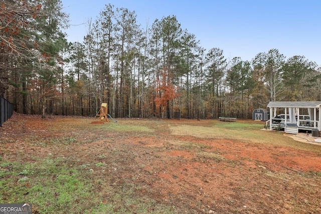 view of yard with an outbuilding, a playground, fence, and a storage shed