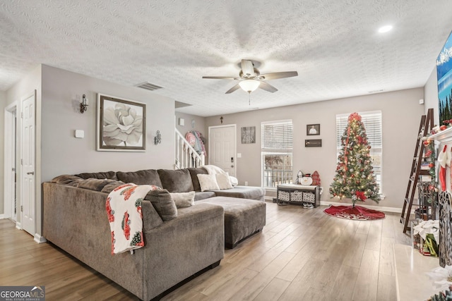 living room featuring ceiling fan, wood finished floors, visible vents, and baseboards