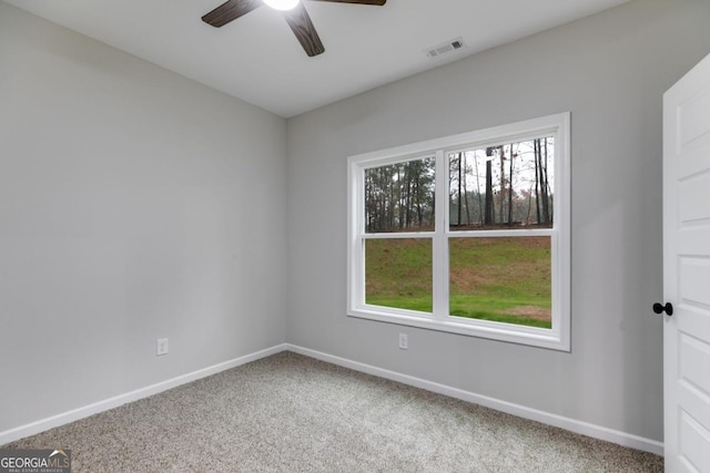 carpeted spare room featuring baseboards, visible vents, and ceiling fan