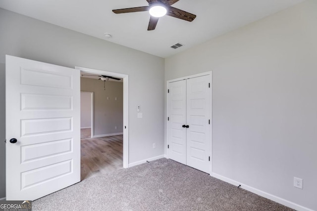 unfurnished bedroom featuring carpet flooring, a ceiling fan, visible vents, baseboards, and a closet