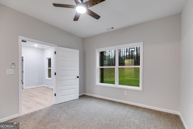 unfurnished room with a ceiling fan, carpet, visible vents, and baseboards