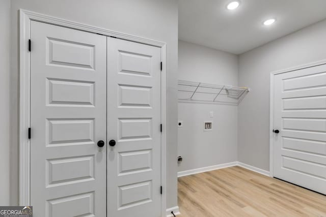 clothes washing area featuring laundry area, light wood finished floors, baseboards, hookup for a washing machine, and electric dryer hookup