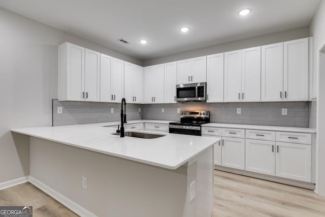 kitchen with light wood-style flooring, stainless steel appliances, a sink, visible vents, and light countertops