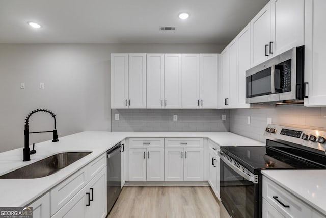 kitchen with a sink, visible vents, white cabinets, appliances with stainless steel finishes, and light wood finished floors