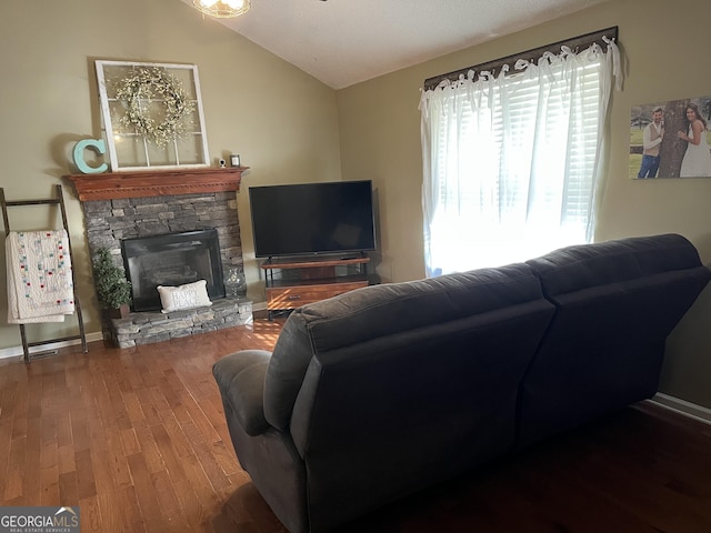 living area with vaulted ceiling, a stone fireplace, wood finished floors, and baseboards