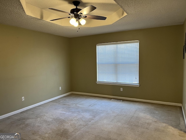 carpeted empty room featuring a textured ceiling, ceiling fan, visible vents, and baseboards