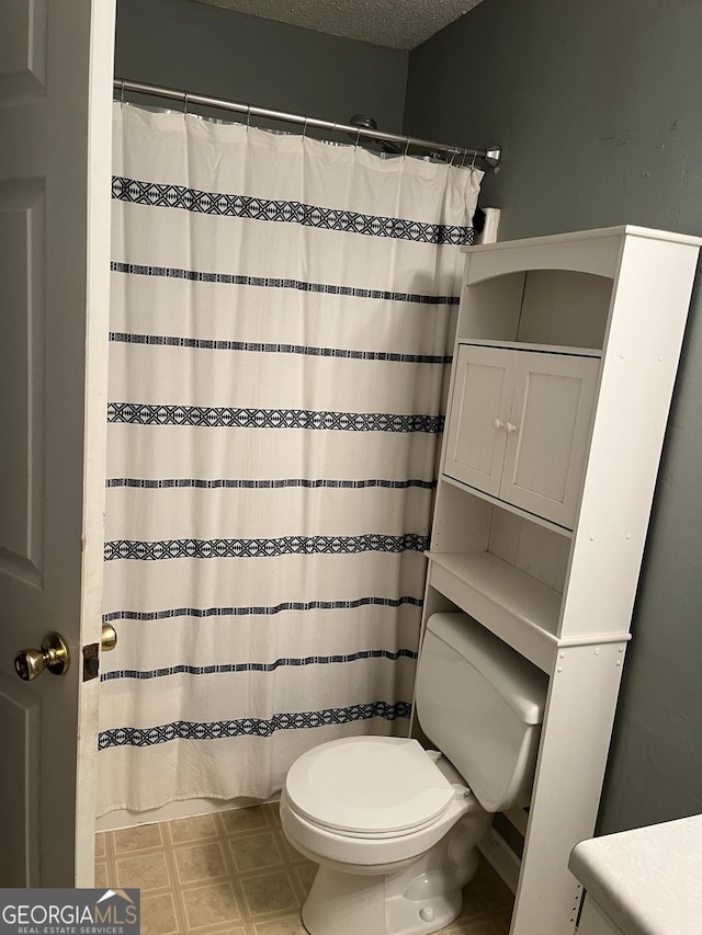 bathroom with a textured ceiling, a shower with shower curtain, and toilet