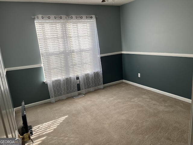 empty room featuring carpet flooring, visible vents, and baseboards