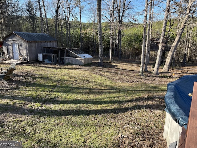 view of yard featuring a shed, an outdoor structure, and a view of trees