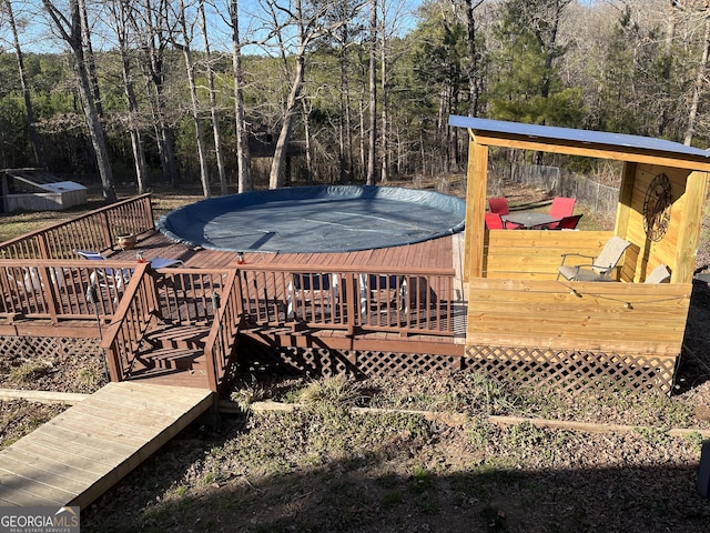 wooden deck with a forest view and a trampoline