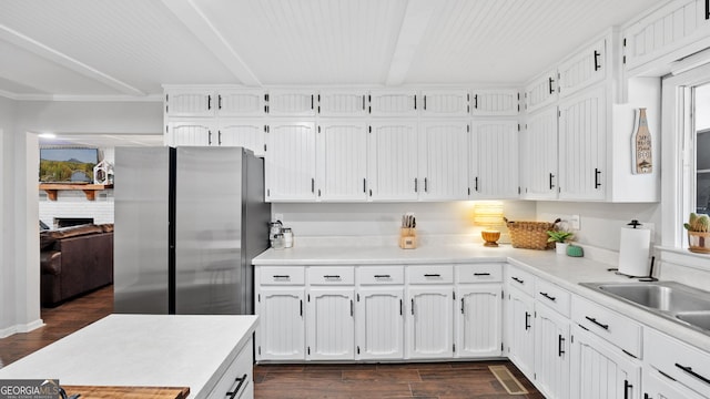 kitchen with dark wood-style flooring, light countertops, freestanding refrigerator, white cabinetry, and beamed ceiling