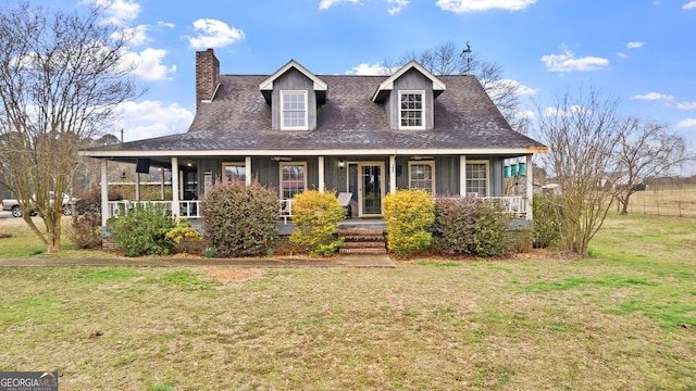 view of front facade with covered porch, a shingled roof, a chimney, and a front lawn