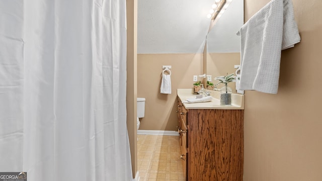 full bath featuring baseboards, toilet, tile patterned floors, vaulted ceiling, and vanity