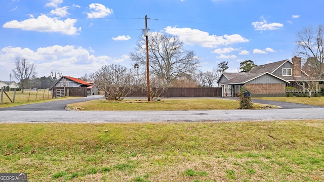 view of yard featuring fence and aphalt driveway