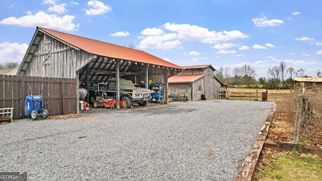 view of pole building featuring a barn, fence, and gravel driveway