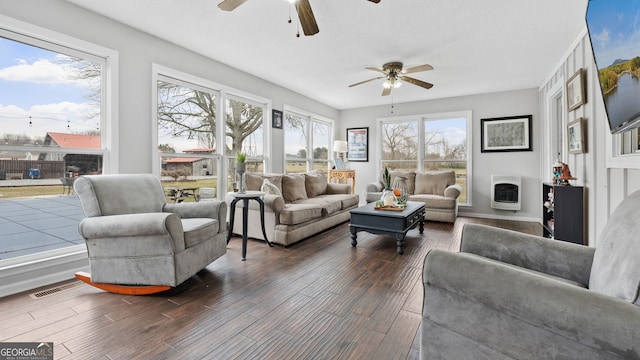 living room featuring visible vents, a fireplace, heating unit, and wood finished floors