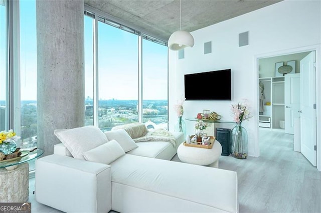 living area featuring a fireplace, wood finished floors, visible vents, and floor to ceiling windows