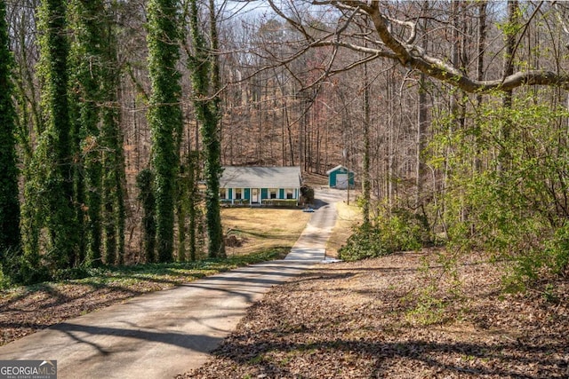 exterior space featuring a view of trees and concrete driveway