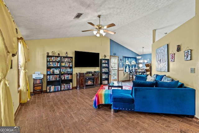 living area with visible vents, vaulted ceiling, a textured ceiling, wood finished floors, and ceiling fan with notable chandelier