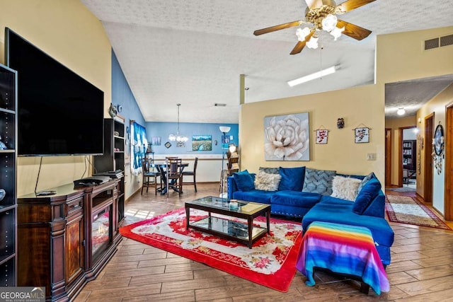 living area featuring vaulted ceiling, wood finish floors, a textured ceiling, and visible vents