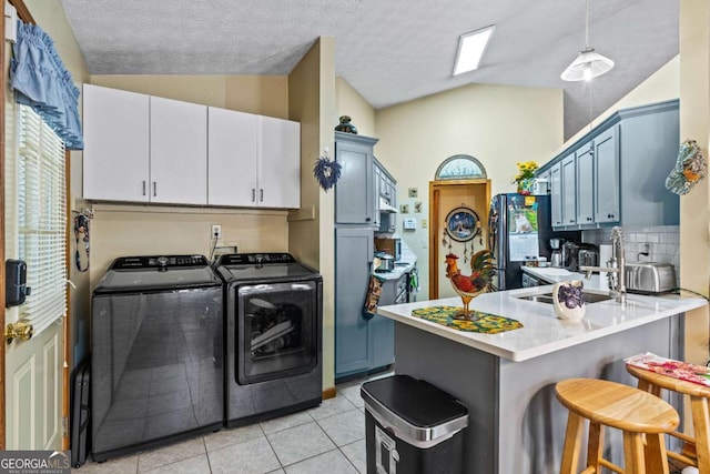 washroom featuring laundry area, light tile patterned floors, a textured ceiling, and separate washer and dryer