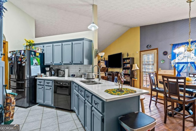 kitchen featuring lofted ceiling, light countertops, a sink, a peninsula, and black appliances