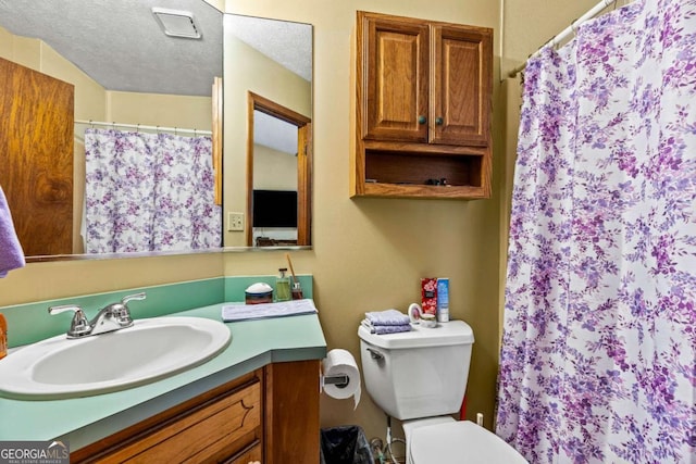 bathroom with toilet, curtained shower, a textured ceiling, and vanity