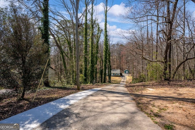 view of road with a forest view and aphalt driveway