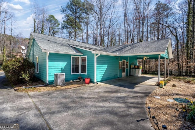 single story home with aphalt driveway, roof with shingles, central AC, fence, and an attached carport