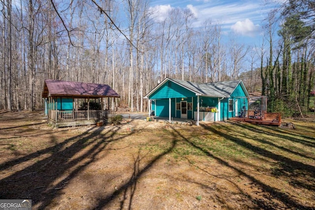 rear view of house featuring dirt driveway, a porch, a lawn, and an outbuilding