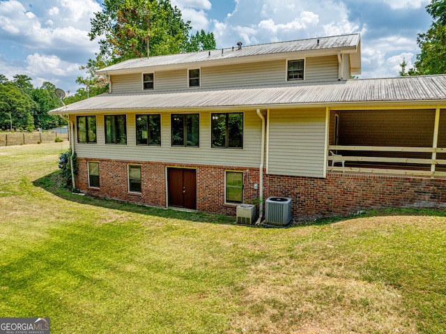 view of front of house featuring metal roof, central AC unit, a front lawn, and brick siding